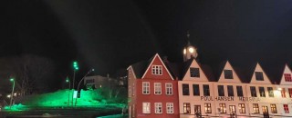 Row of buildings at night with green street lights.