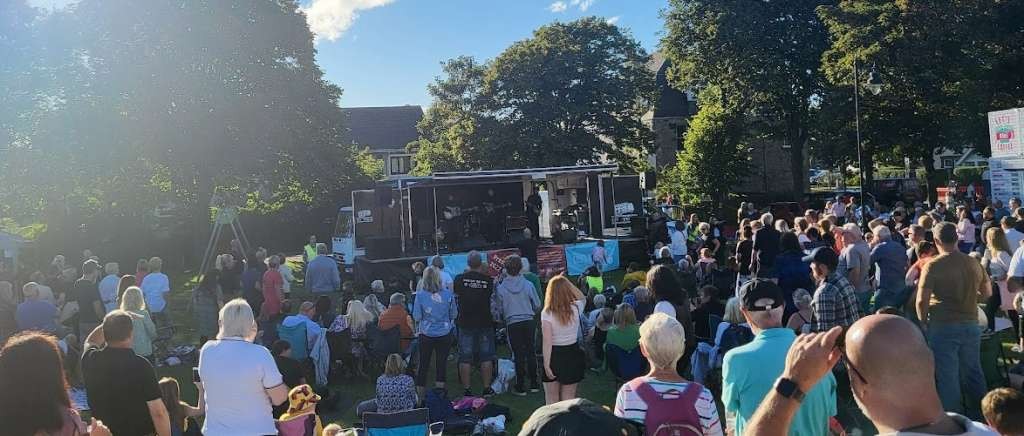 Outdoor music stage with crowd of people gathered round