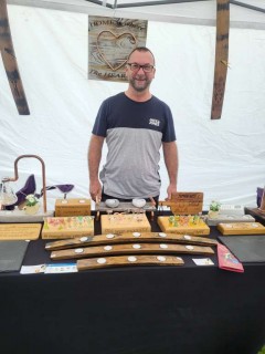 Man standing in a stall full of wood carvings and ornaments.
