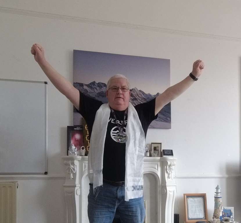 Man standing with arms aloft wearing a medal.
